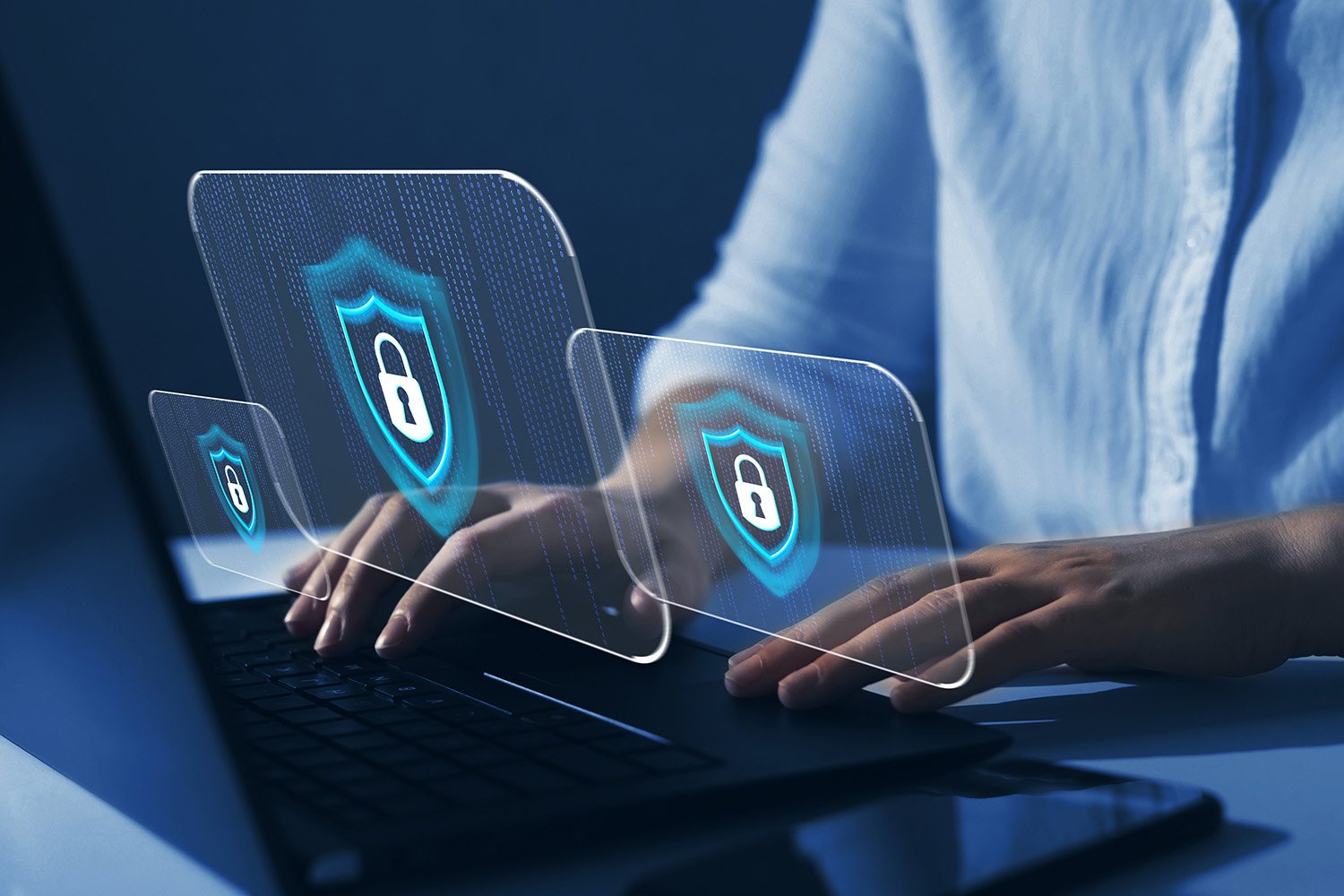 Man vid bärbar dator, virtuella skärmar med säkerhetsikon i luften ovanför tangentbordet